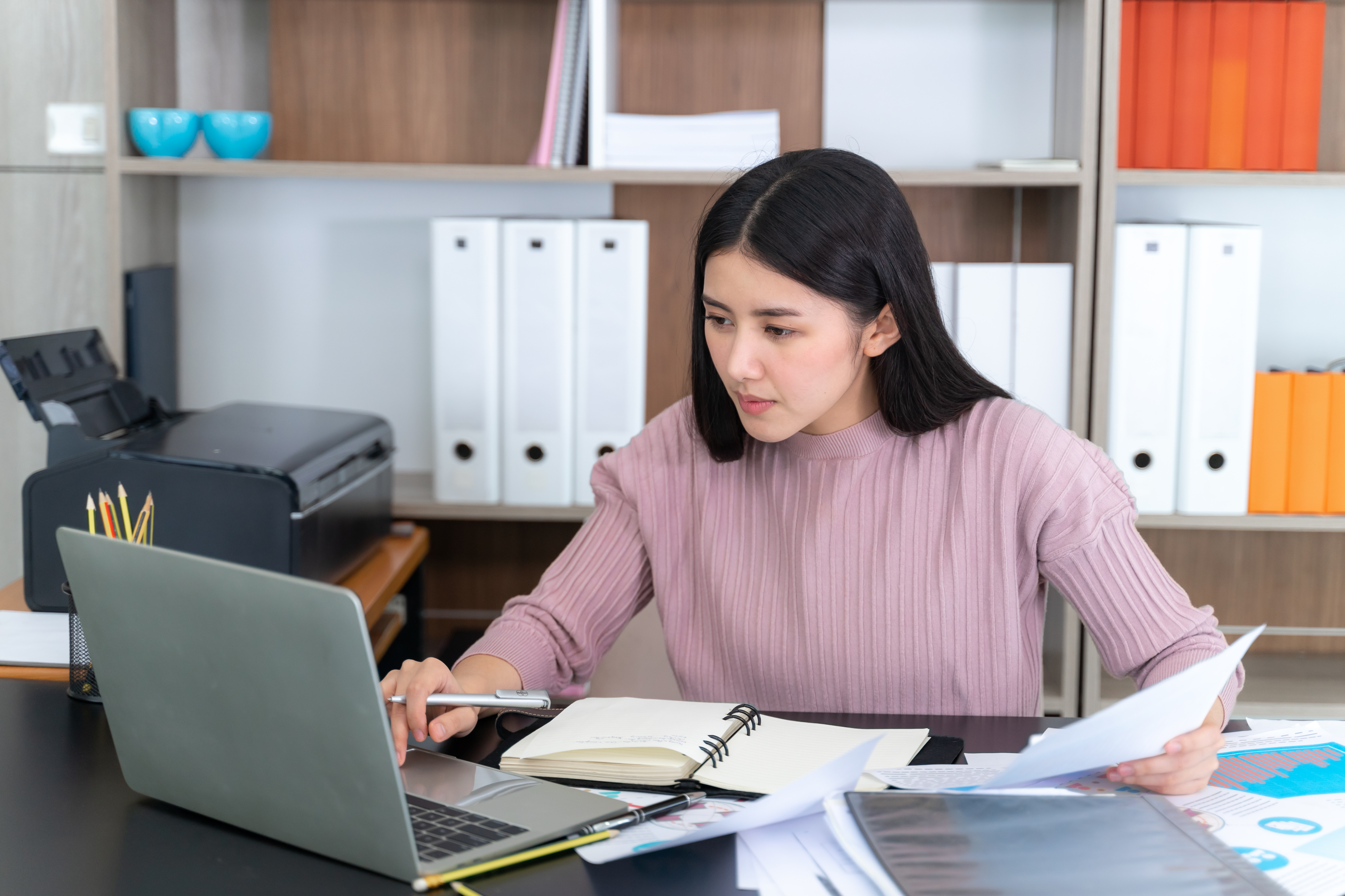 Remote Administrative Assistants reviewing reports and working on laptop in office workspace